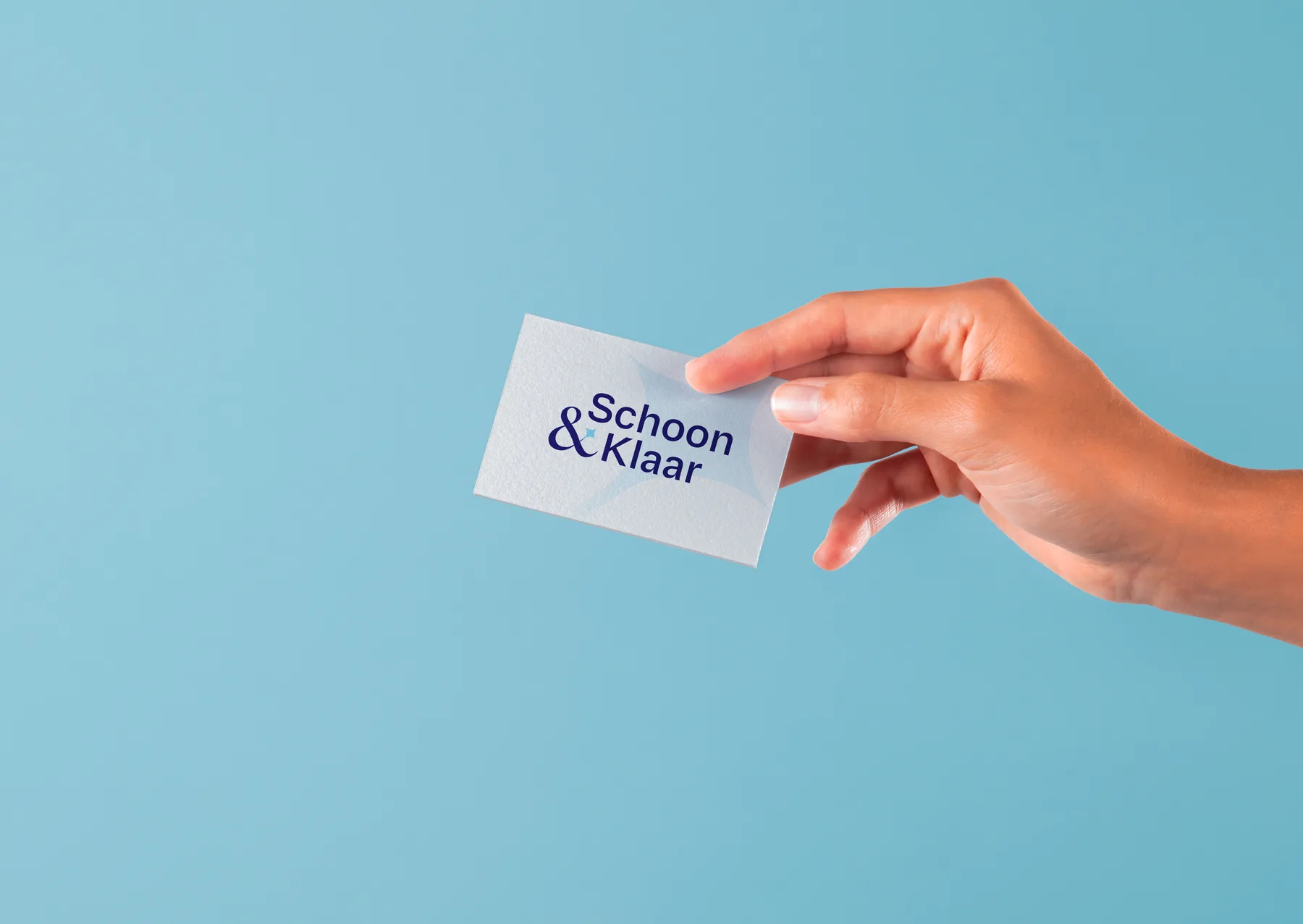 A business card with a new logo, held against a blue background